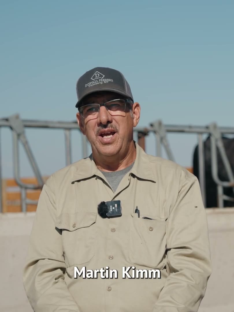 Farmer Martin Kimm in a cap and tan jacket talking to camera in front of a bridge, his name on screen