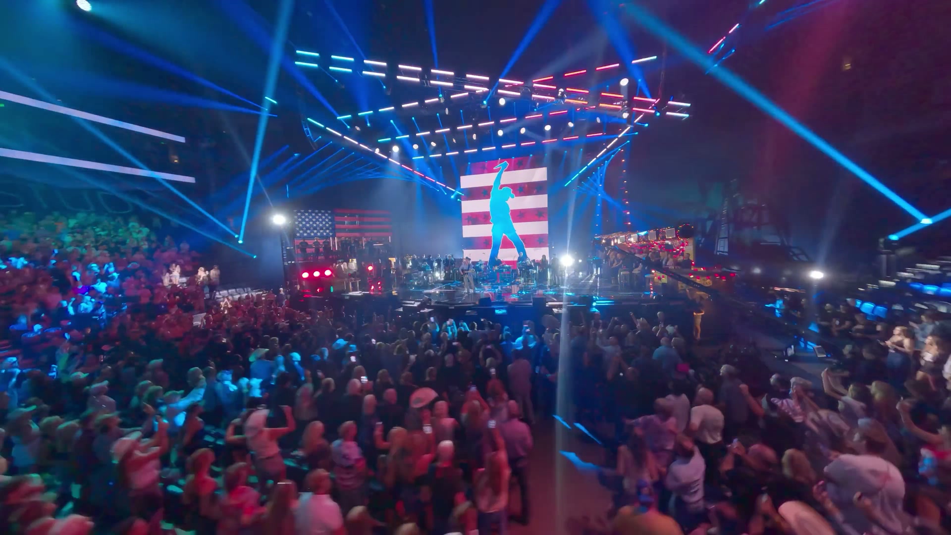 Crowd under a laser-lit stage rig at the Toby Keith memorial event